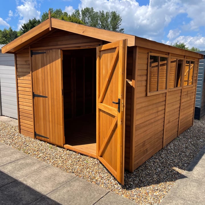 This 10ft x 12ft Malvern Heavy Duty Apex is constructed with cedar cladding. Optional upgrades as shown include; double doors and a black felt tiled roof.