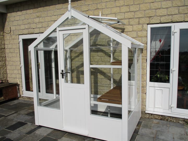 This 6ft x 4ft Swallow Kingfisher greenhouse has the optional 'Lily White' painted finish. 
Optional high level shelving has been added to this greenhouse.