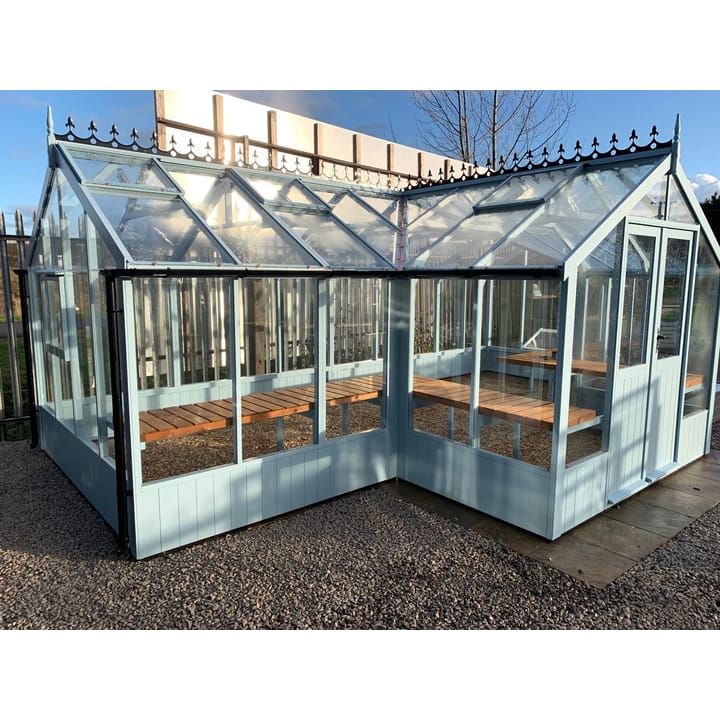 8ft 9in deep x 21ft 1in wide Swallow Swan t-shaped greenhouse. The Swan incudes front returned staging which sits at the front of the greenhouse and wraps around into the porch area. Optional 'Lulworth Blue' painted finish has been applied. The Swan can be constructed in either dwarf wall format or as pictured here freestanding. There is no extra cost for the dwarf wall option.