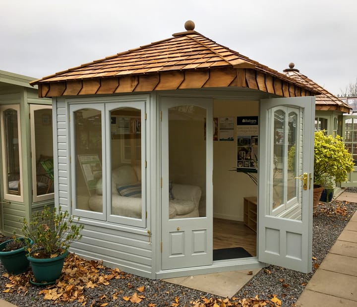 This 8ft x 8ft Clifton in Dove Grey looks absolutely stunning. The 'cottage' style arched windows really add a decorative touch. Brass has been chosen for the door and window furniture. 

One point worth knowing: If you opt for the double glazing upgrade, the arched top of the windows become square to accommodate the double glazed units.