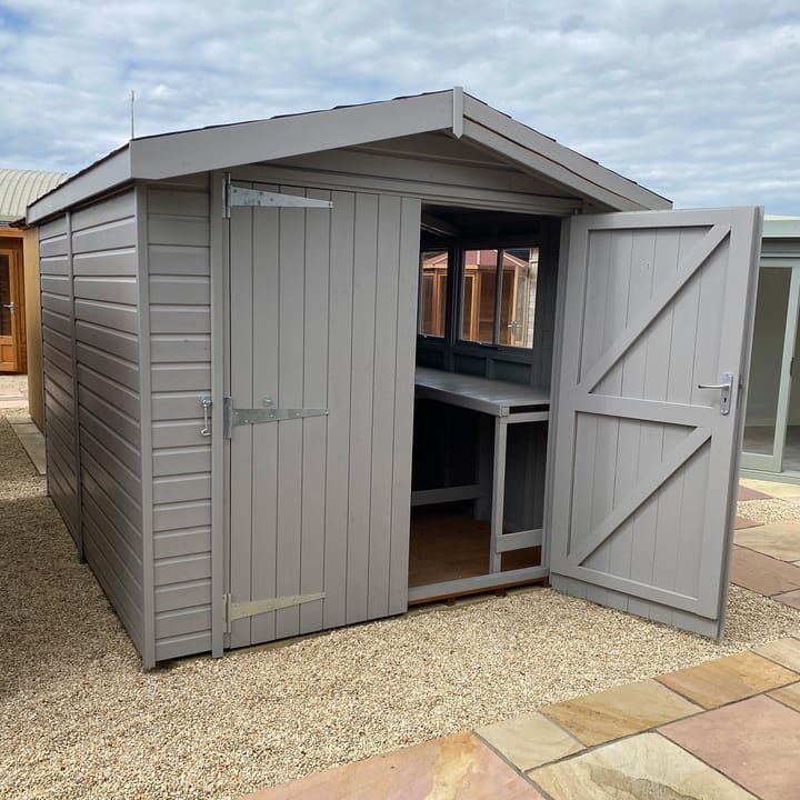 This 8ft x 10ft Heavy Duty Apex is constructed in heavy duty redwood cladding. A roof overhang and opening windows(s) are standard features. Ironmongery is available in a choice of black or as pictured here chrome. Optional felt tiles, double doors, workbench and a painted finish in urban grey have all been added.