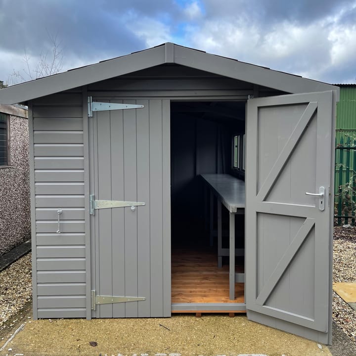 This 8ft x 10ft Heavy Duty Apex is constructed in heavy duty redwood cladding. A roof overhang and opening windows(s) are standard features. Ironmongery is available in a choice of black or as pictured here chrome. Optional felt tiles, double doors, workbench and a painted finish in urban grey have all been added.
