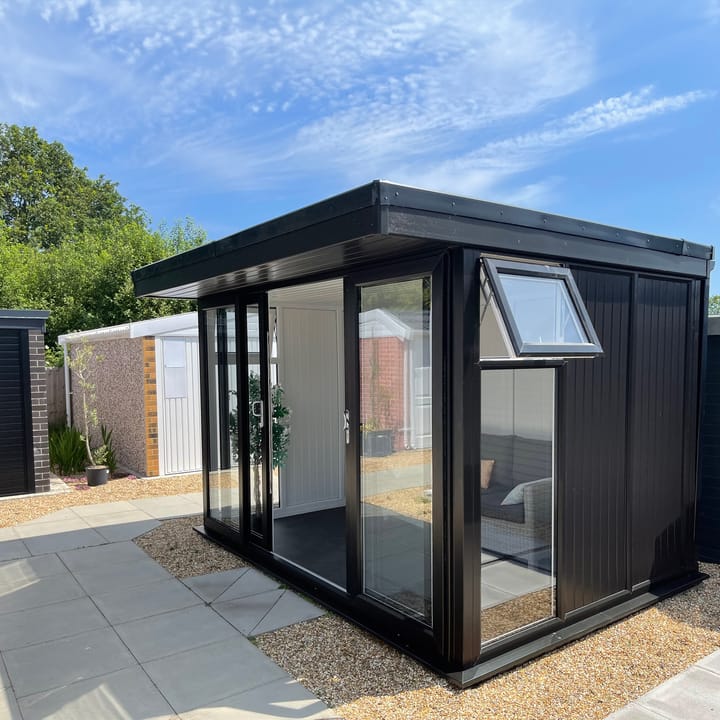 Nordic Broadway Flat 3.6m x 2.4m in Black. The Broadway Flat includes large double sliding doors to the front. A glass to ground window with a top opening vent is positioned in each end, towards the front. The fully glazed front of the building allows plenty of natural light without obscuring the view.