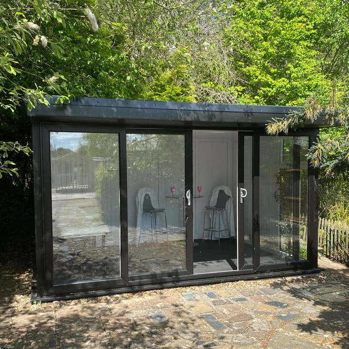 Nordic Broadway Flat 4.2m x 3m in Black. The Broadway Flat includes large double sliding doors to the front. A glass to ground window with a top opening vent is positioned in each end, towards the front. The fully glazed front of the building allows plenty of natural light without obscuring the view.