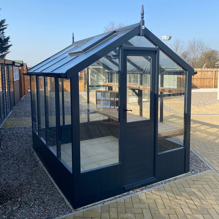 This 6ft x 8ft Swallow Kingfisher greenhouse has the optional 'Railings' painted finish.Optional high level shelving and guttering have been added to this greenhouse.