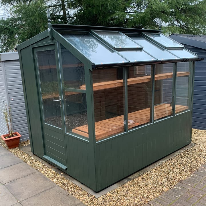 This 6ft x 8ft Swallow Jay greenhouse has the optional 'Olive Green' painted finish. Optional additional high level shelving and guttering have been added to this greenhouse.