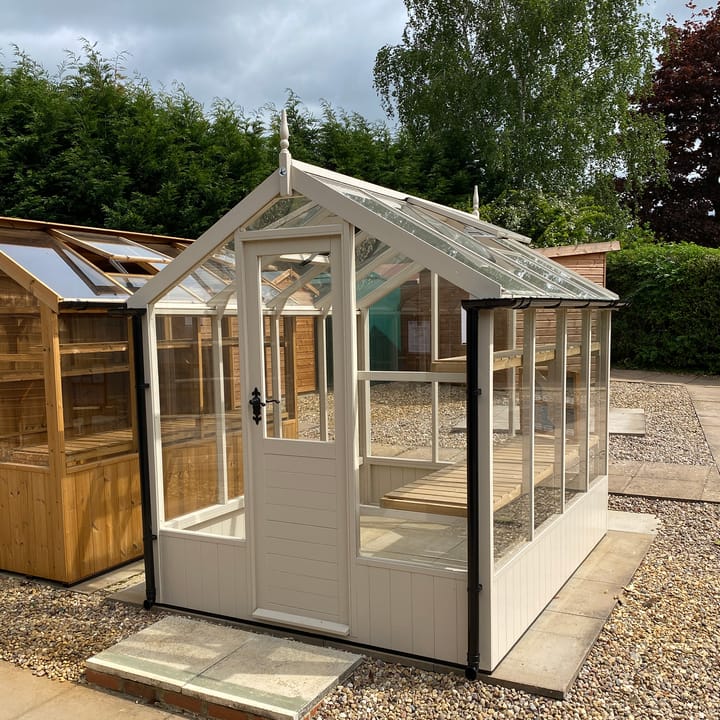This 6ft x 8ft Swallow Kingfisher greenhouse has the optional 'Oxford Stone' painted finish. Optional high level shelving and guttering have been added to this greenhouse.